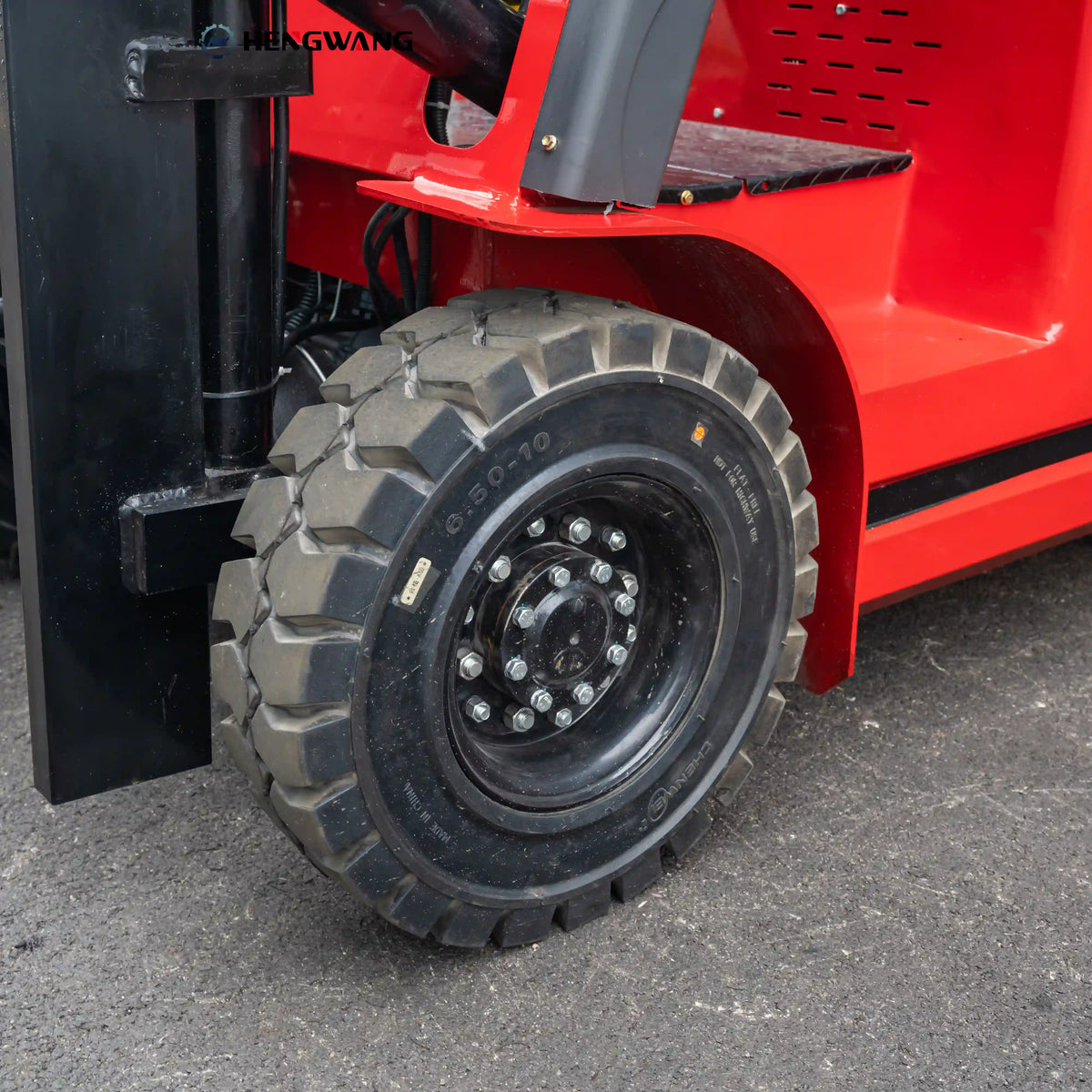 Close-up of a heavy-duty 6.50-10 deep-tread rubber tire on a 6,500 lb electric forklift, mounted on a multi-bolt steel wheel for durable traction on warehouse and concrete floors.