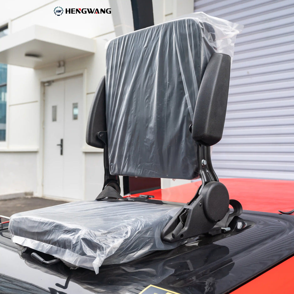 Close-up of the black vinyl operator seat on a 6,500 lb electric forklift, featuring padded backrest, flip-up armrests, and seat suspension mount for all-day warehouse operation comfort.