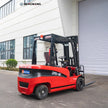 Rear three-quarter view of a 6,500 lb 60V electric forklift showing heavy rear counterweight, overhead guard with amber warning beacon and LED work lights, and deep-tread rubber tires for warehouse operation.