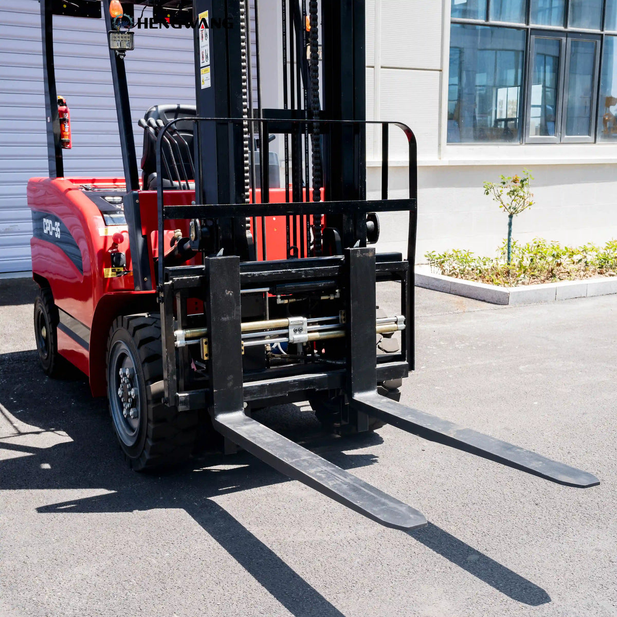 Close-up of 48-inch steel forks and hydraulic side shifter on a 7700 lb electric forklift, outdoor view