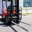 Close-up of 48-inch steel forks and hydraulic side shifter on a 7700 lb electric forklift, outdoor view