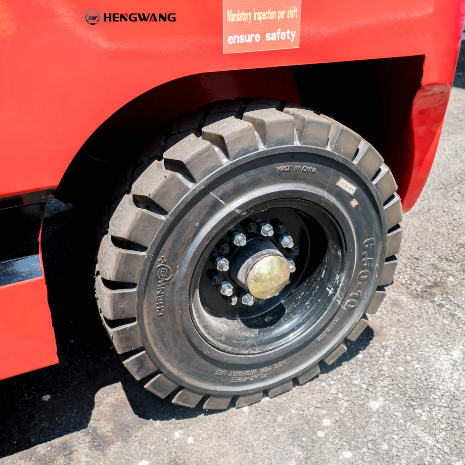 Close-up of heavy-duty 6.50-10 rear tire on a 7700 lb electric forklift, showing deep tread and bolted wheel hub