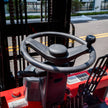 Close-up of steering wheel with spinner knob and dashboard controls inside a 7700 lb electric forklift