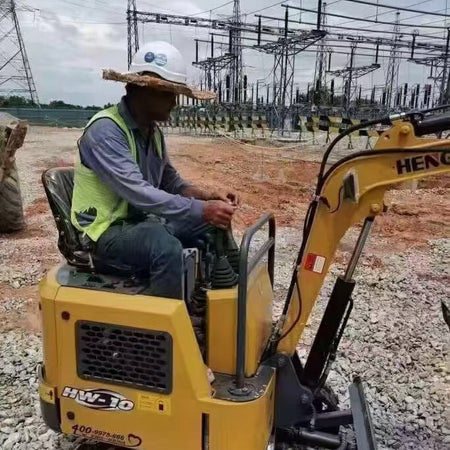 Worker operating Hengwang HW-10 compact mini excavator at electrical power station construction job site
